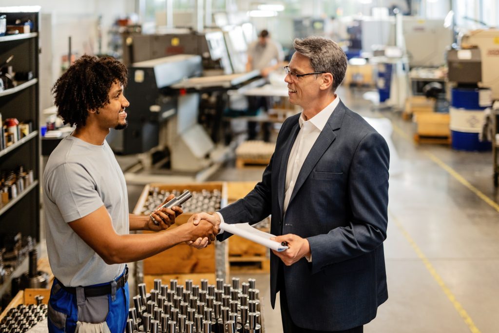 Businessman greets African-American worker at an industrial plant